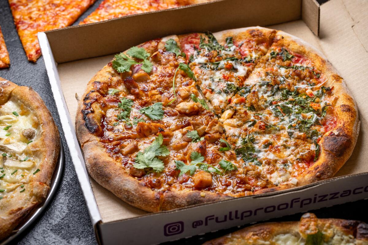 A photo of a spread of pizzas, one in a to-go box, from Full Proof Pizza.