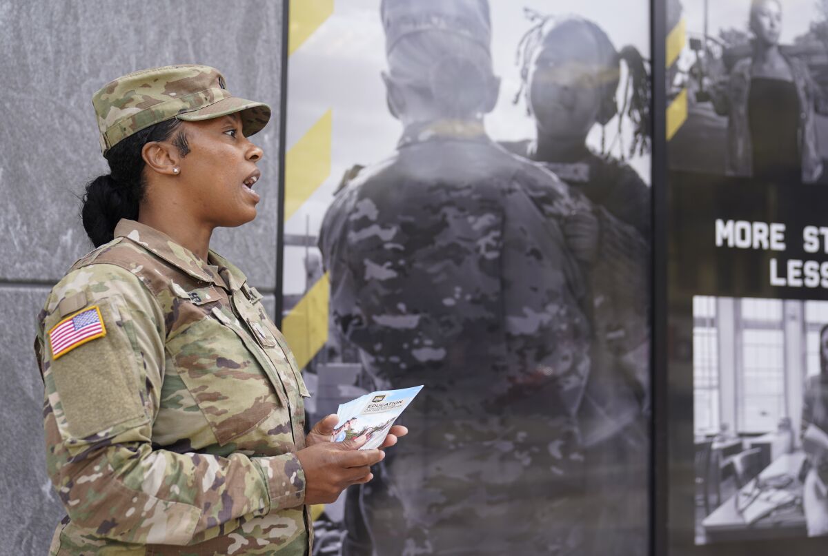The U.S. Army National Guard member Sgt. Jessica Jones, an officer with the Metropolitan Police Department, distributes brochures to people walking by during training, Thursday, April 21, 2022 in Washington. In March the local guard opened its first proper recruiting office in the city since 2010. The commander, Maj. Gen. Sherrie McCandless, describes the move as a new push for visibility and an emphasis on the guard’s local connections at a time when many residents might be ripe for recruitment. (AP Photo/Mariam Zuhaib)