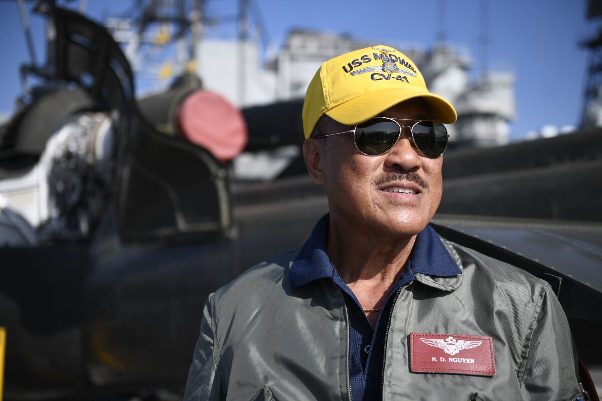 Nguyen Dinh Nguyen poses for a photo on the flight deck of the Midway next to a Huey helicopter on Nov. 13. Nguyen flew Hueys and other aircraft during the Vietnam War.