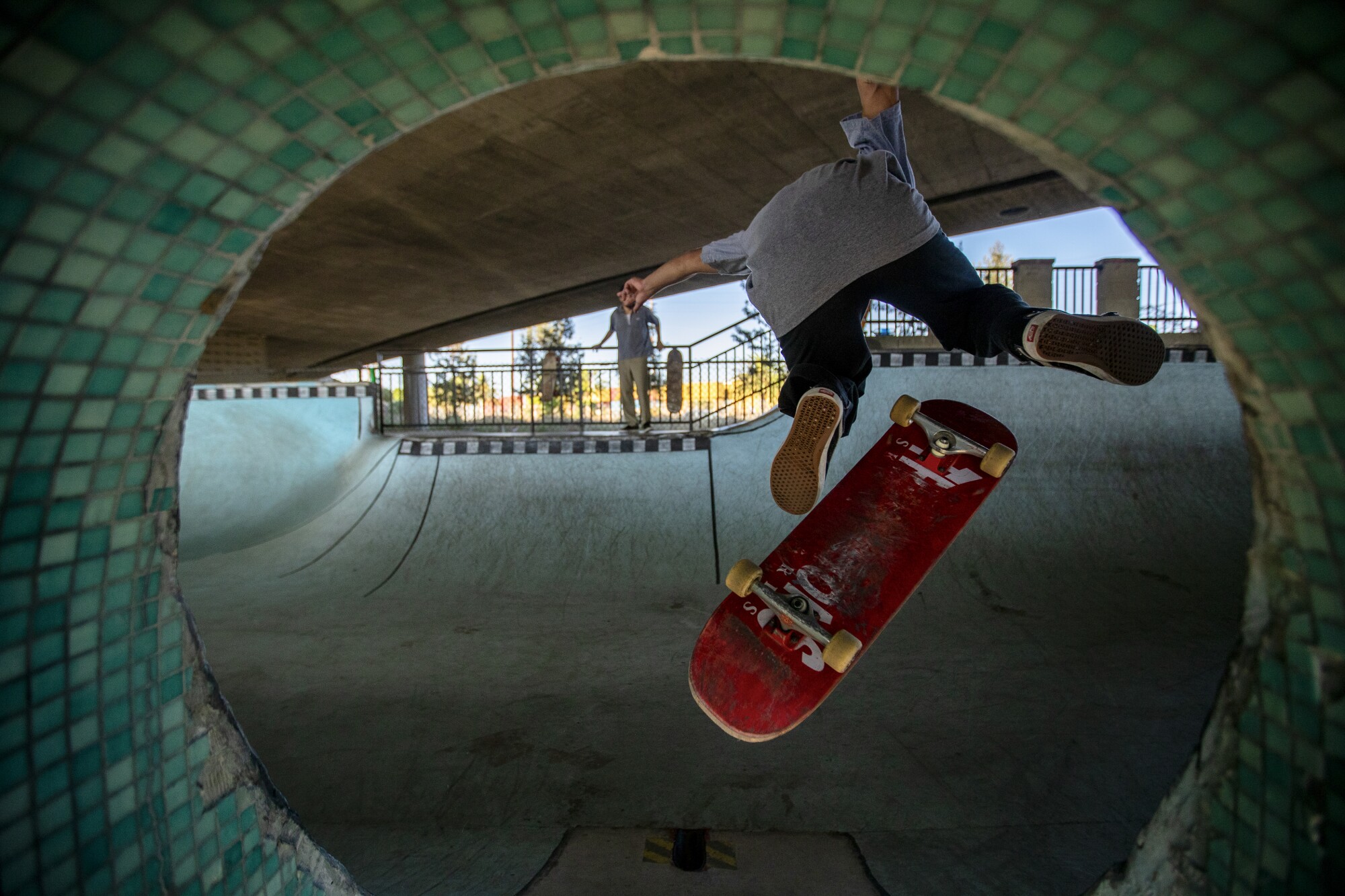 A skateboarder does a trick over a pedestrian tunnel at the Channel Street Skatepark.