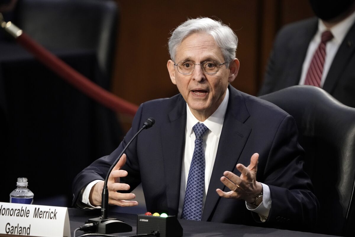 Merrick Garland is seen gesturing in front of a microphone