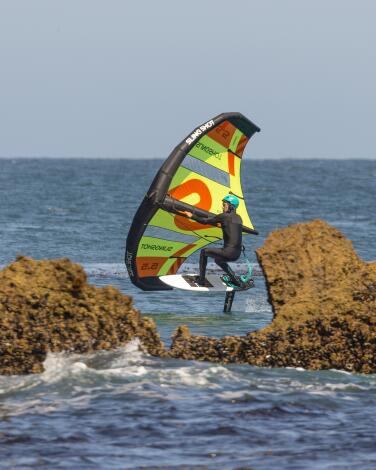 A kite foil boarder rides past a rock at Leo Carrillo State Beach.