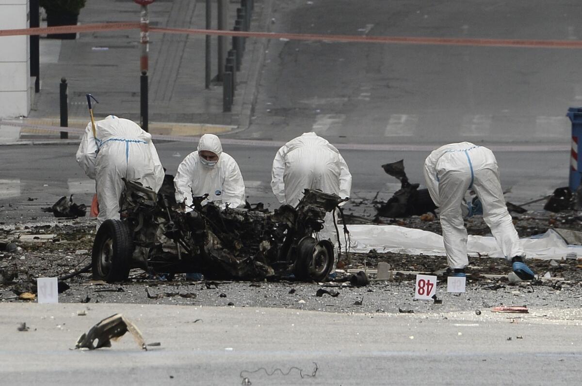Police search the wreckage of a booby-trapped car that exploded outside the Bank of Greece in Athens.