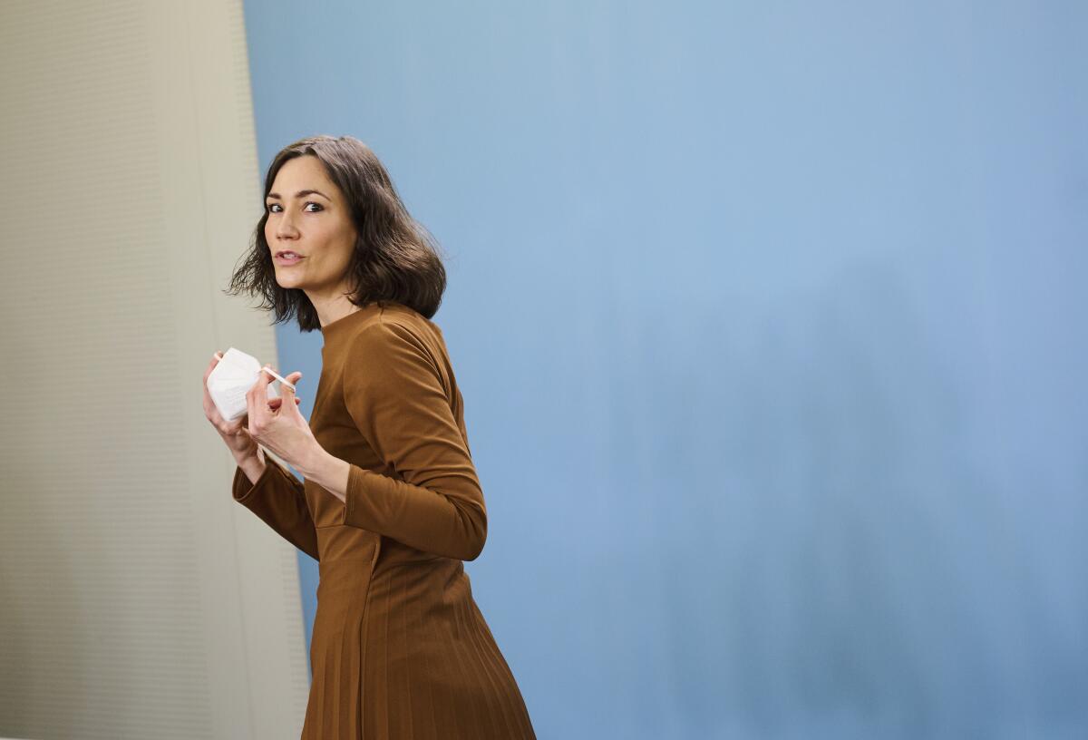 Anne Spiegel walks and holds a face mask.