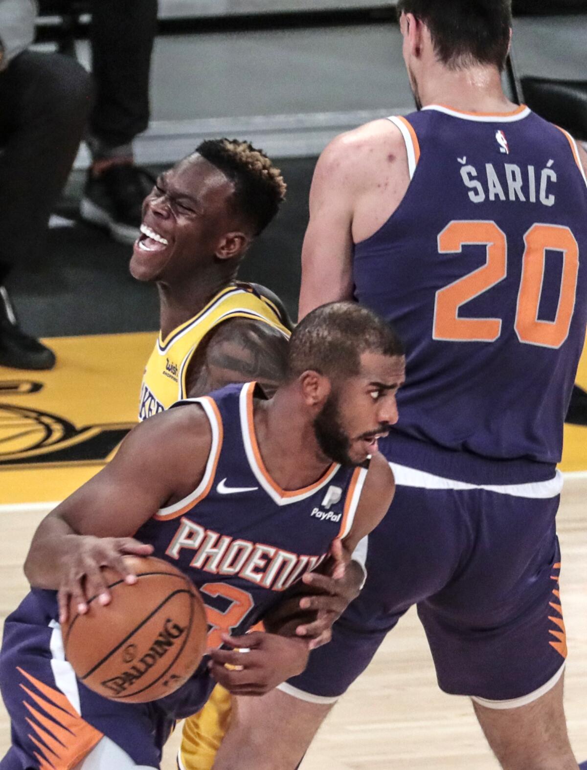 Lakers guard Dennis Schroder tries to cover Phoenix guard Chris Paul as Dario Saric sets a screen.