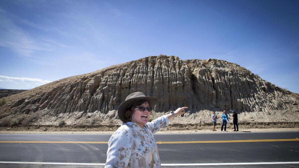 Lucy Jones, center, stands directly on the San Andreas fault and points to an area of the hillside where the rocks abruptly change, a sign of where the fault is located.