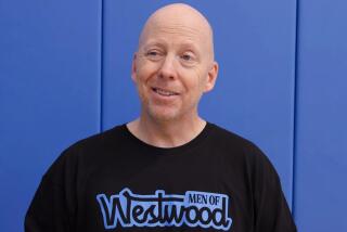 UCLA men's basketball coach wears a Men of Westwood t-shirt while speaking to reporters.