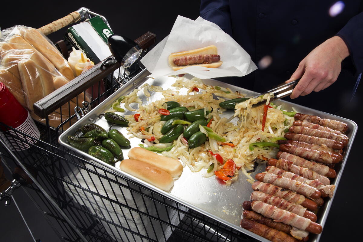 A hand at a DIY bacon-dog street cart