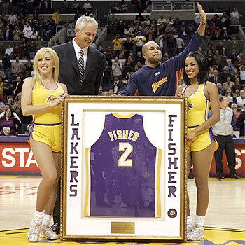 Former Laker Derek Fisher acknowledges the crowd after receiving a framed jersey from Laker General Manager Mitch Kupchak before the start of the Lakers against the Warrior at Staples Center.