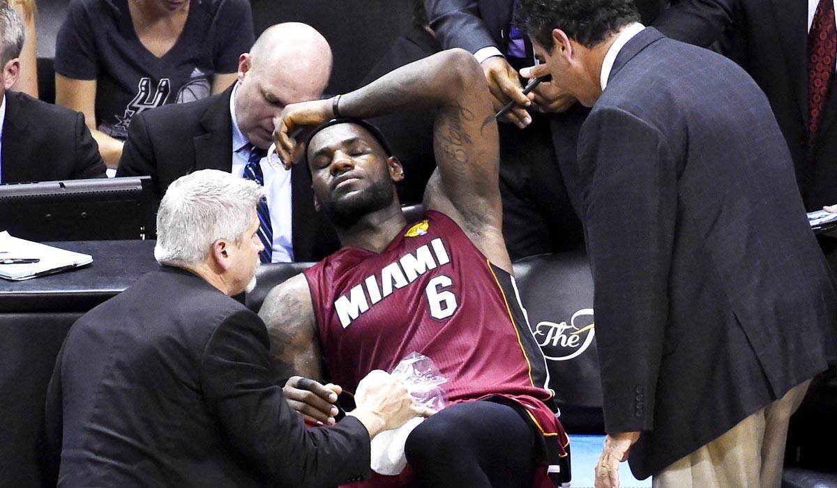 Heat forward LeBron James receives treatment for cramps in his left leg late in the fourth quarter of Game 1.