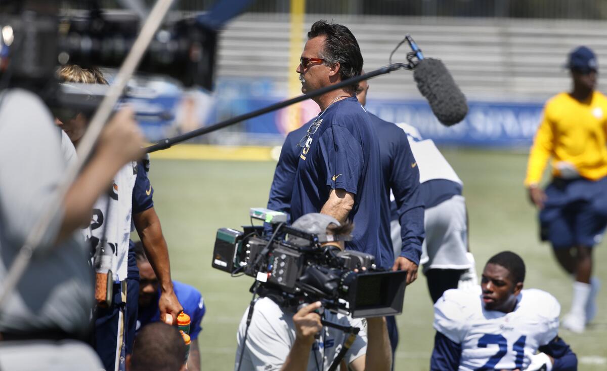 Rams Coach Jeff Fisher walks past "Hard Knocks" cameras and boom microphones during a workout at UC Irvine on Aug. 1.