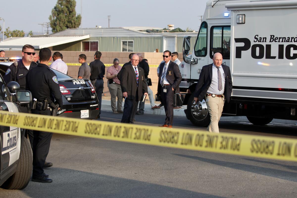 People stand behind crime scene tape