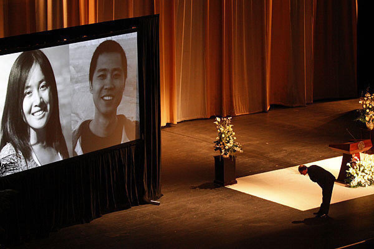 USC President C.L. Max Nikias bows before images of slaying victims Ying Wu and Ming Qu during a memorial service in the Shrine Auditorium.