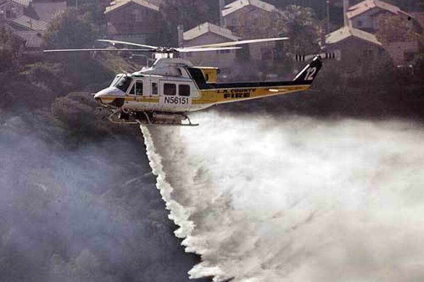 A helicopter drops water on a blaze in the north end of Saugus in the Santa Clarita Valley.