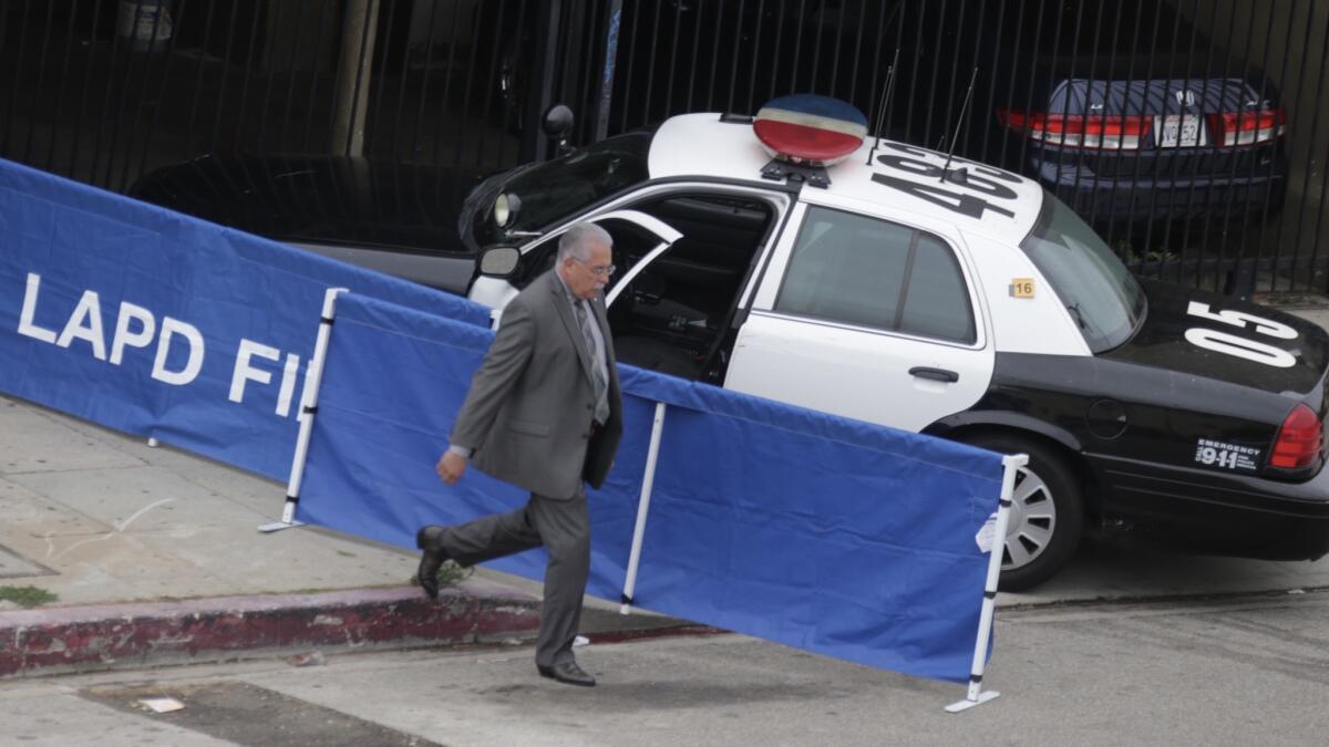 An LAPD investigator cordons off a police car as part of an investigation into last week's fatal police shooting of a 20-year-old man in Wilmington. Chief Charlie Beck said that Eric Rivera fell to the ground after he was shot and was then struck by the officers' vehicle.