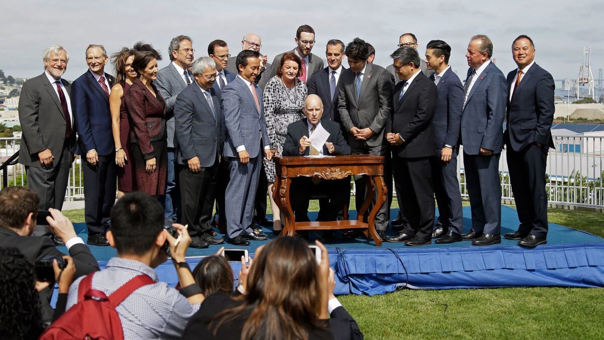 California Gov. Jerry Brown holds up a number of bills he signed to help address housing needs as a group of elected officials and housing advocates look on Sept. 29 in San Francisco.