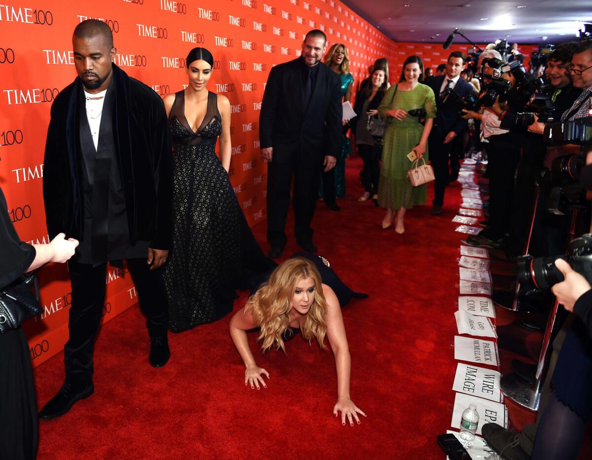 Comedian Amy Schumer pretends to trip and fall on the floor in front of honorees Kim Kardashian and Kanye West at the Time 100 Gala at Lincoln Center on Tuesday in New York.