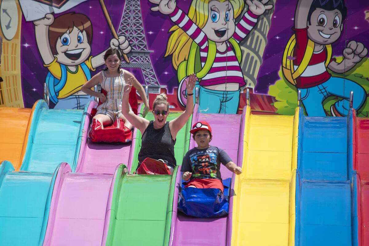 Fairgoers slide down a large, multicolored slide