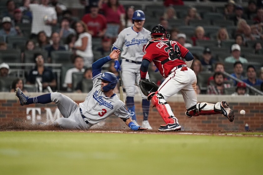 Chris Taylor slides safely into home plate to score for the Dodgers past Atlanta Braves catcher William Contreras.
