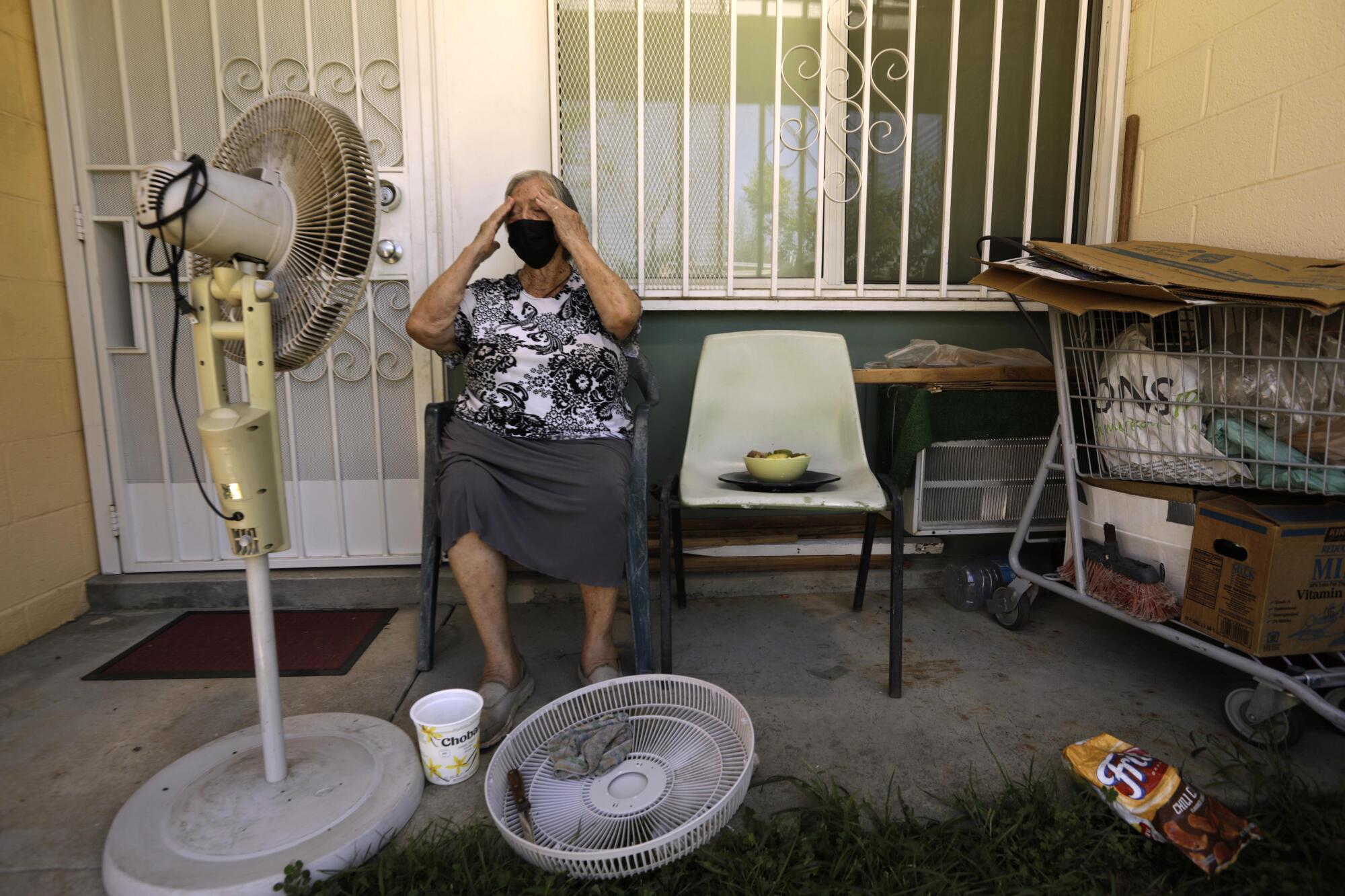 Felisa Benitez wipes the sweat from her brow while taking a break from cleaning her stand-up electrical fan in Pacoima