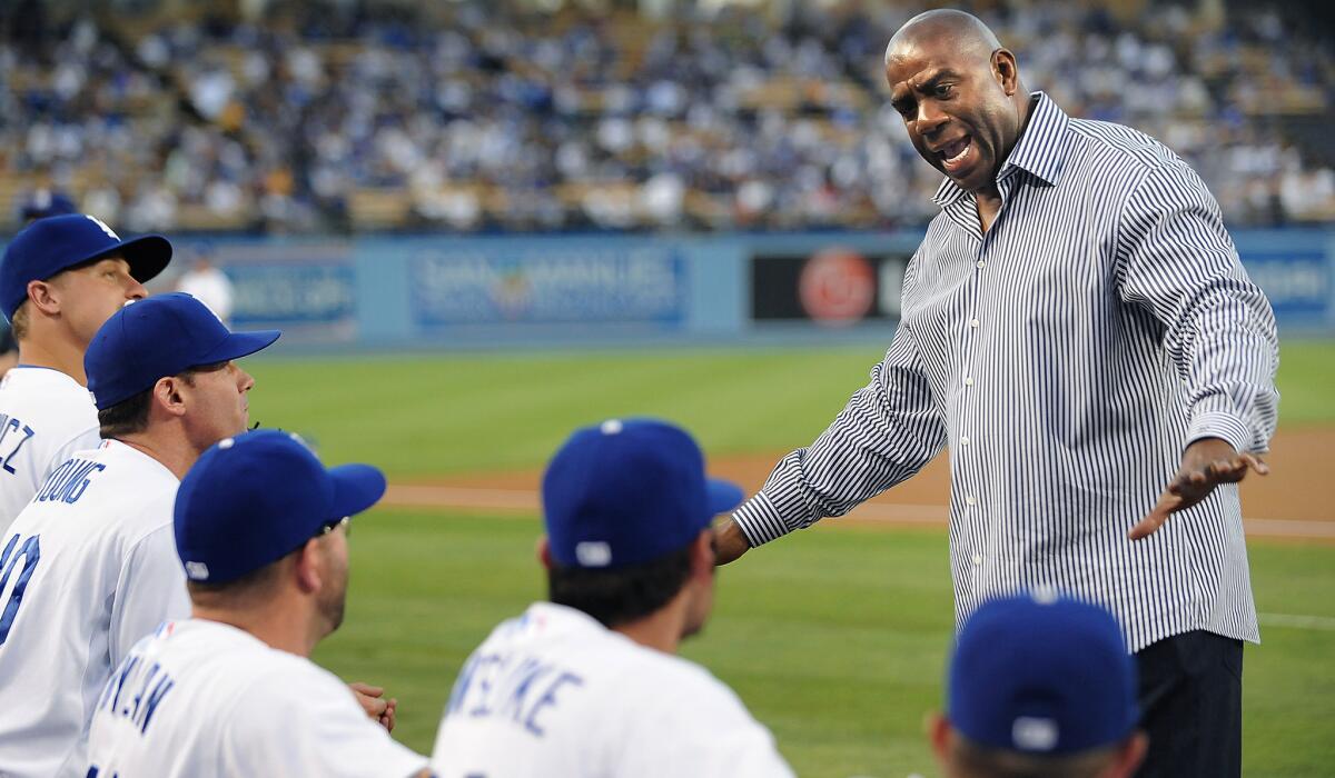 Magic Johnson talks with Dodger players before a game against the Giants last season at Dodger Stadium.