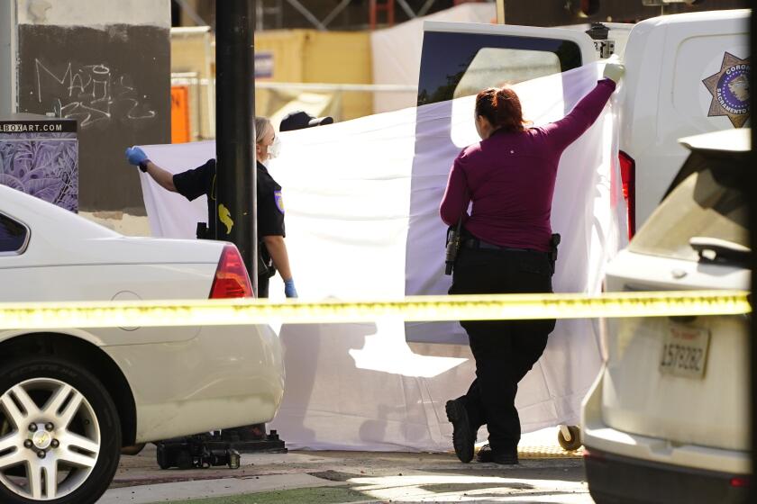 A sheet is used to block the view as the body of one of victims is loaded into a coroner's van
