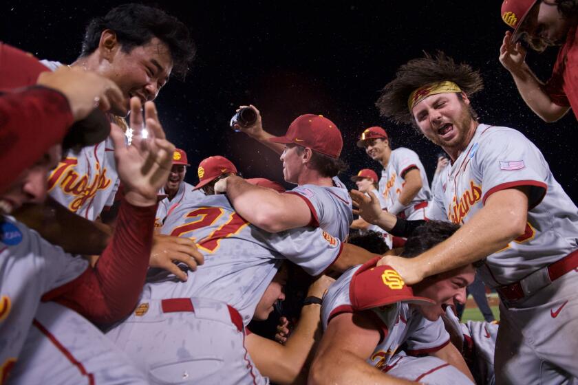 USC baseball players jump on a pile on the Texas A&M baseball field after defeating the Aggies to win their regional.