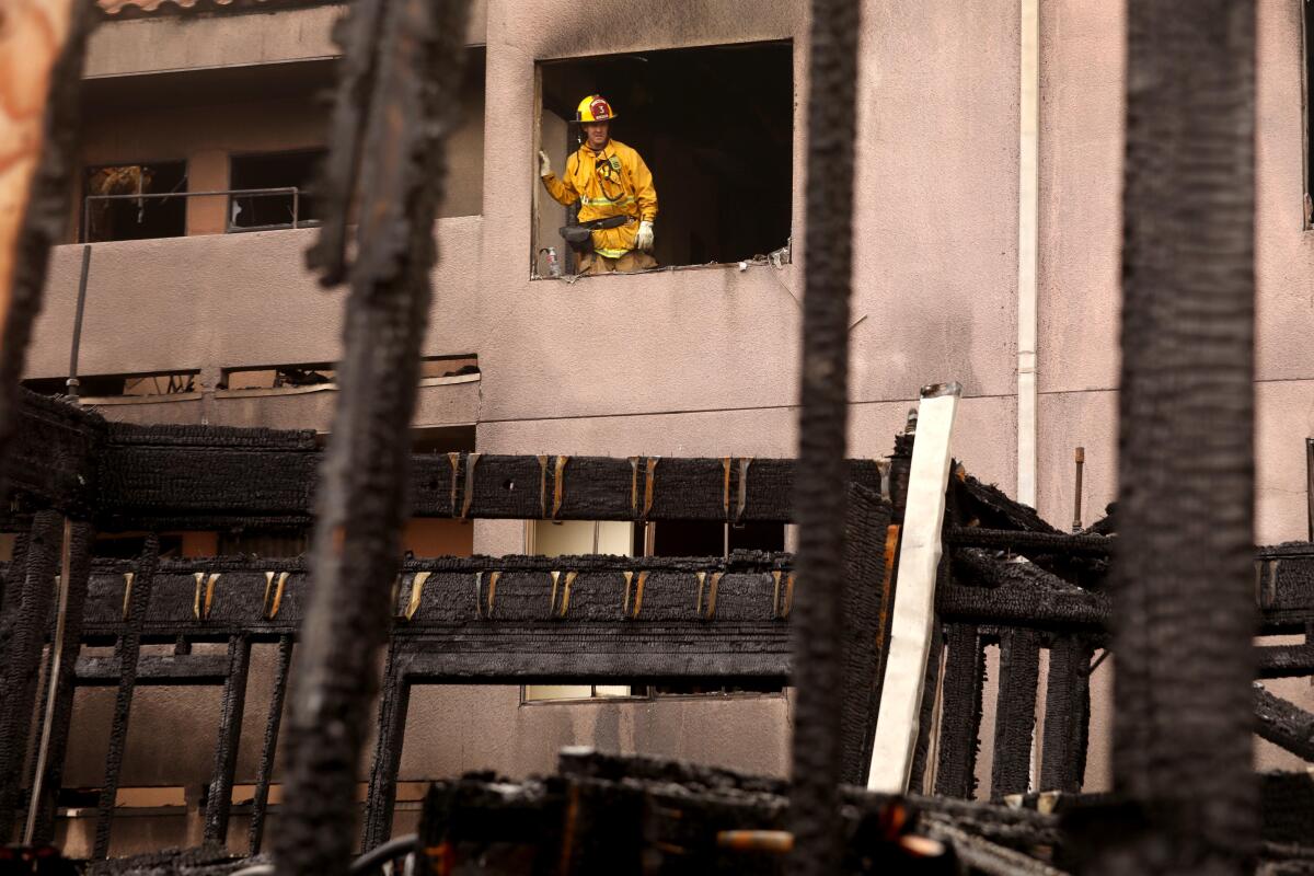 A firefighter looks out from a fire damaged apartment over the remnants of a three story building