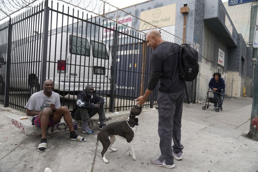 El veterinario Kwane Stewart pregunta a la gente por el dueño de un perro en la zona Skid Row de Los Ángeles, el 7 de junio de 2023. Stewart, de 52 años, es un amante de los animales de toda la vida que creció en Texas y Nuevo México tratando de ayudar y cuidar a perros callejeros. (AP Foto/Damian Dovarganes)