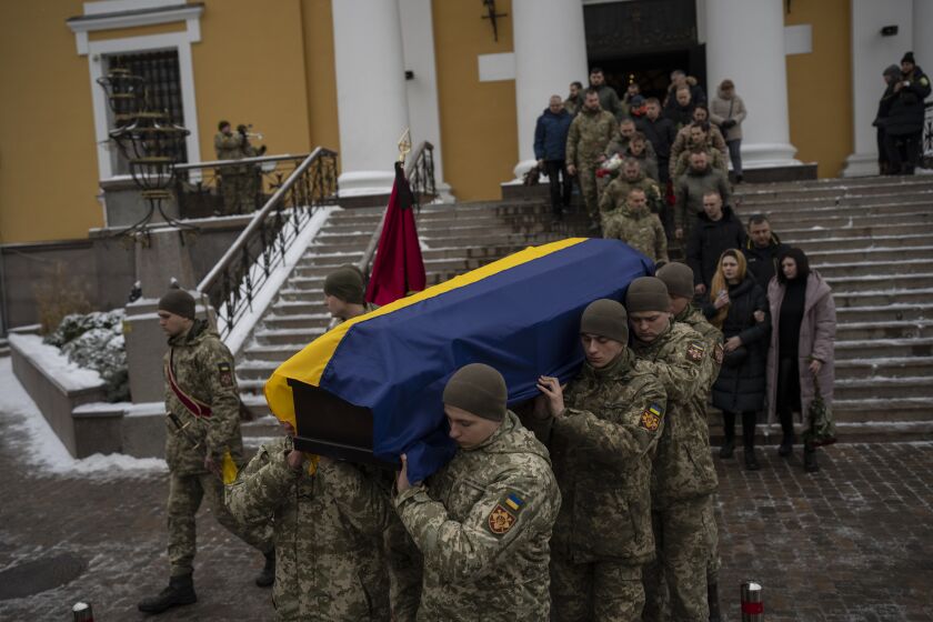 Soldiers carry the coffin of Eduard Strauss, a Ukrainian serviceman who died in combat on Jan. 17 in Bakhmut, during a farewell ceremony in Kyiv, Ukraine, Monday, Feb. 6, 2023. (AP Photo/Daniel Cole)