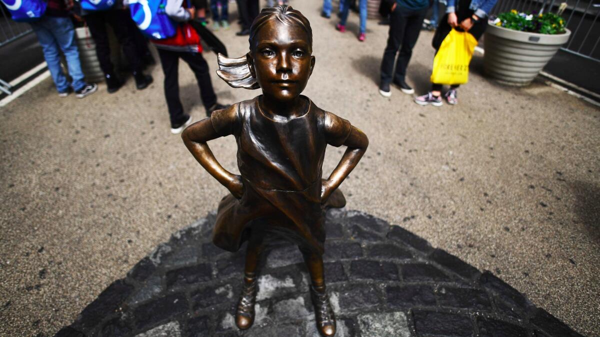 The "Fearless Girl" statue stands facing the Charging Bull statue as tourists take pictures in New York on April 12. (Jewel Samad / AFP/Getty Images)