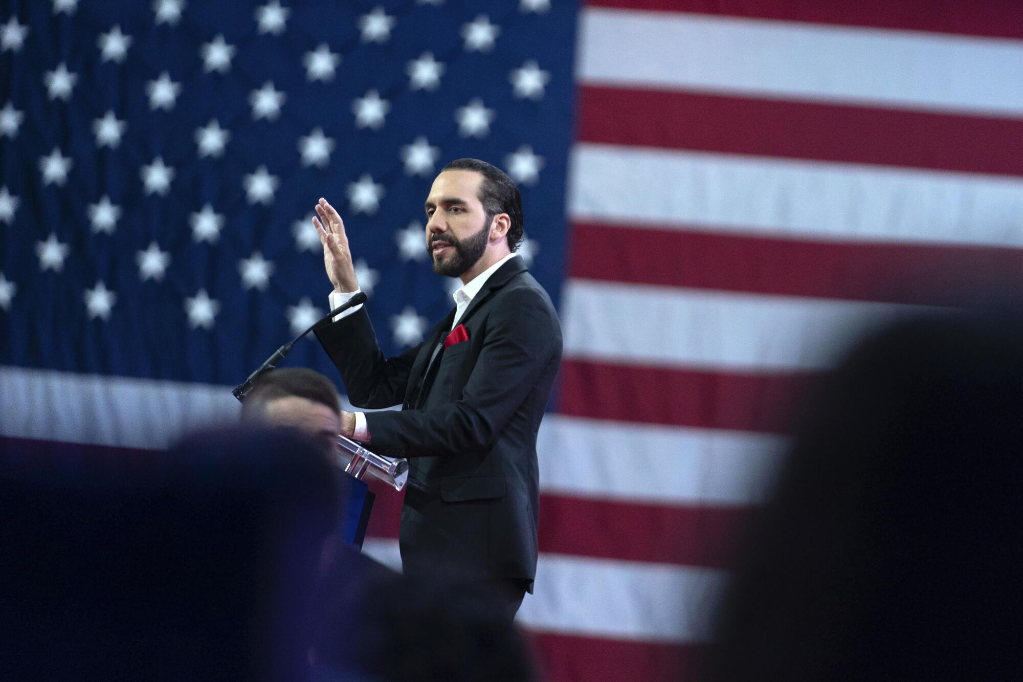 Nayib Bukele speaks in front of a giant image of the United States flag.