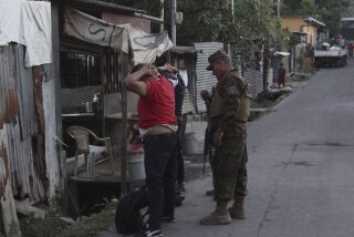 Soldados revisan las identificaciones de dos hombres en la comunidad 1 de Diciembre, un territorio bajo el control de la pandilla Mara Salvatrucha en Soyapango, El Salvador, el lunes 5 de diciembre de 2022. (AP Foto/Salvador Melendez)