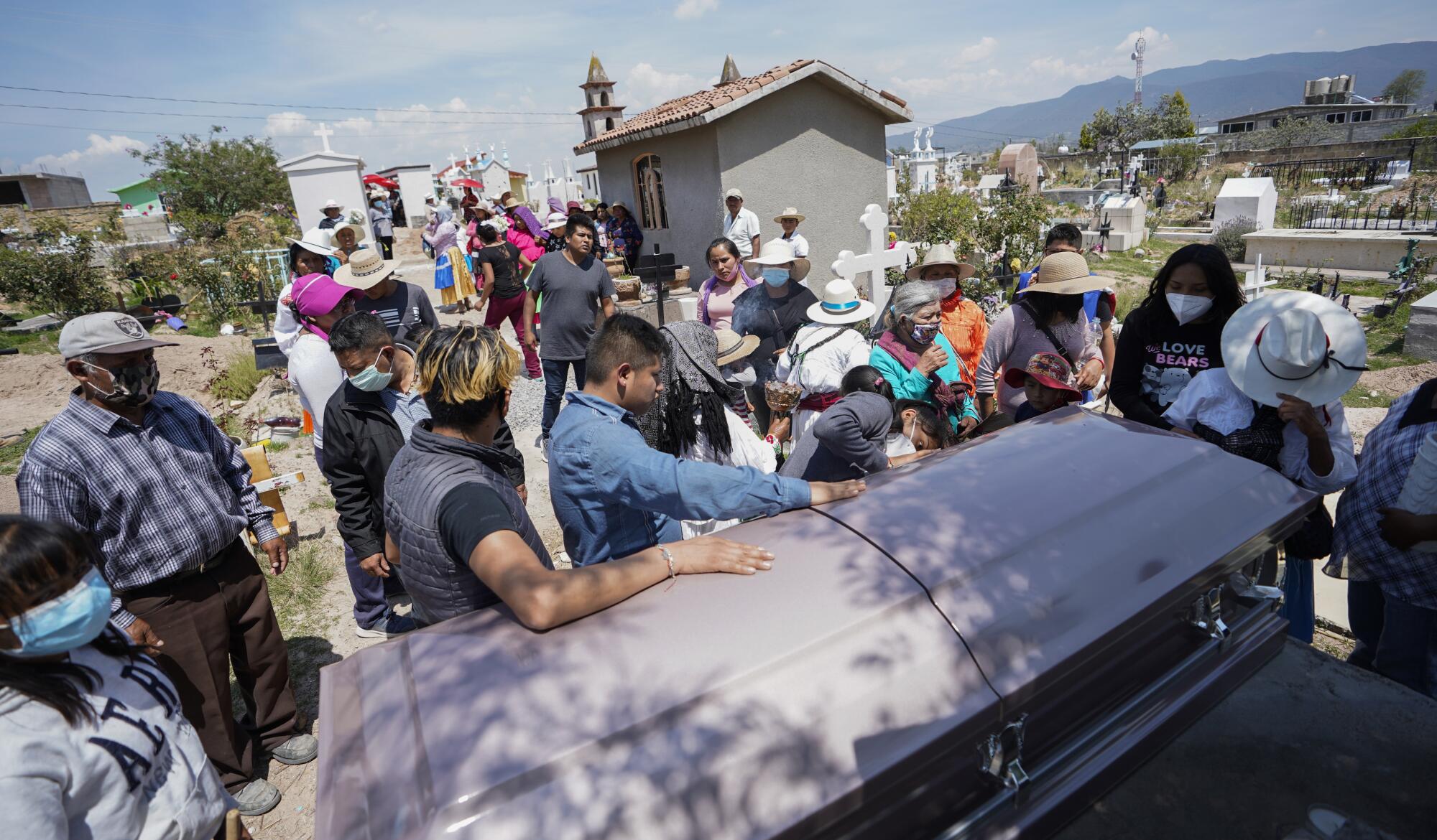 People gather around a casket at a cemetery 