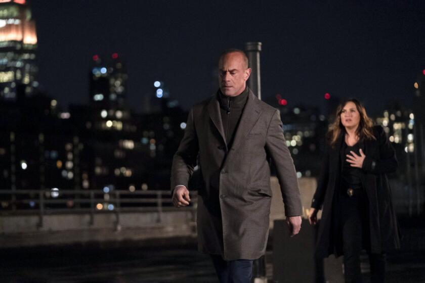 A man strides away from a woman on a New York City rooftop at night