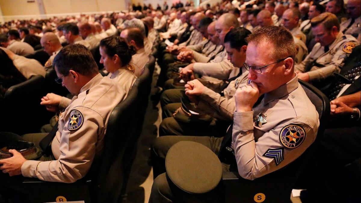 Ventura County Sheriff's deputy Dan McLaughlin, right, holds hands with other deputies as requested during a closing prayer at a memorial service for Sgt. Ron Helus, who was one of 12 victims of the Borderline Bar and Grill mass shooting in Thousand Oaks.