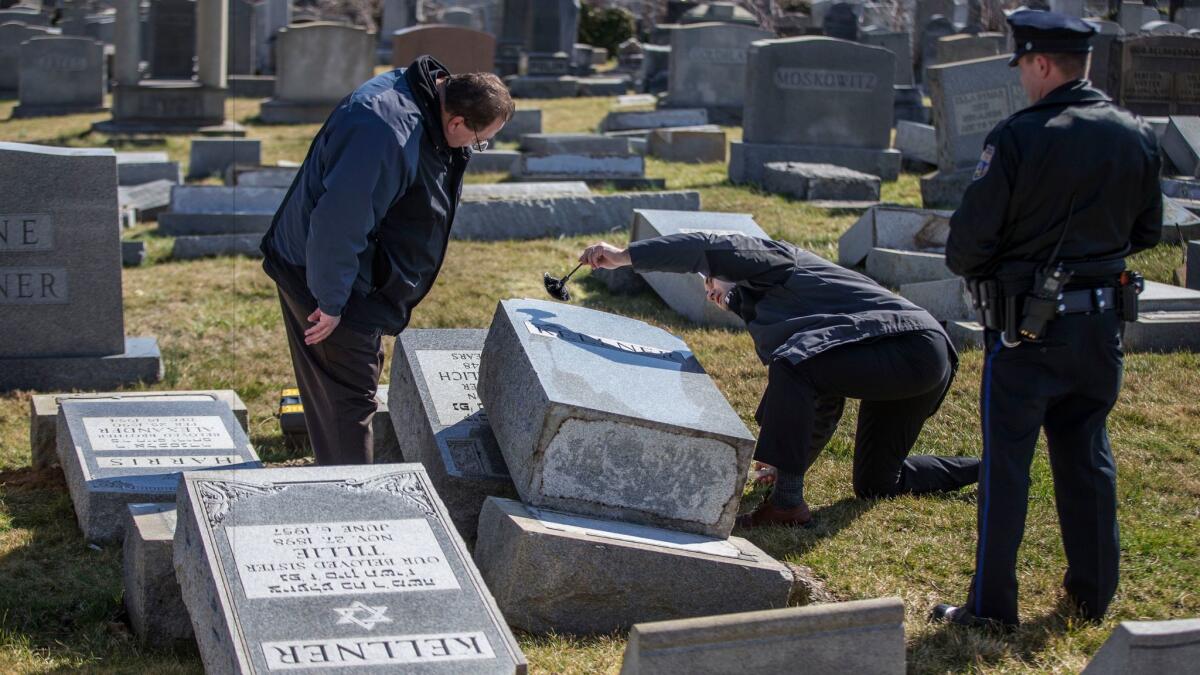Police on Sunday dust for fingerprints on a headstone that was knocked down at Mt. Carmel Cemetery in Philadelphia.