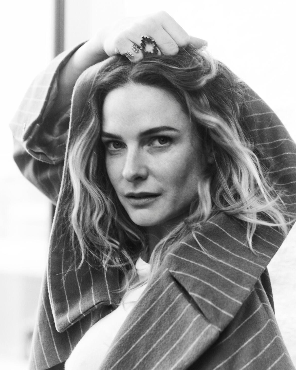 In a black-and-white portrait, Rebecca Ferguson pulls her jacket up around her head.