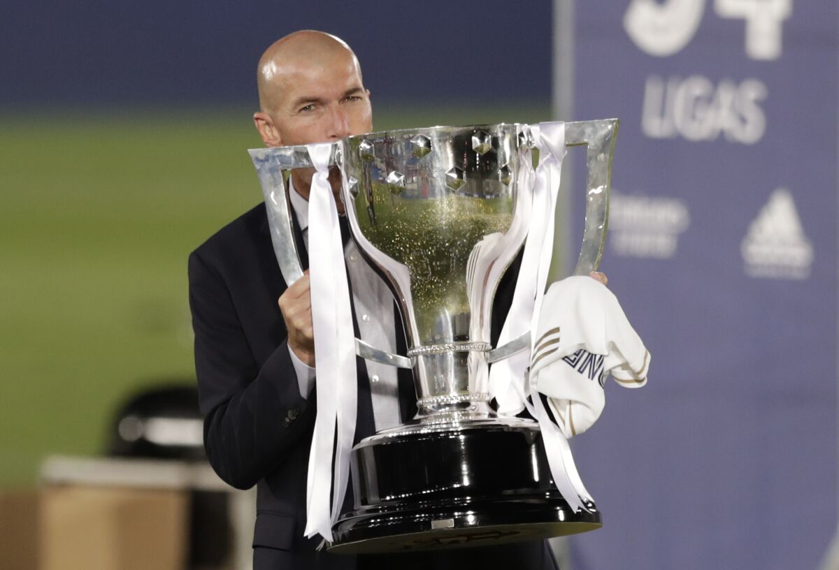 Real Madrid's head coach Zinedine Zidane, holds the trophy as he poses for the photographers after winning the Spanish La Liga 2019-2020 following a soccer match between Real Madrid and Villareal at the Alfredo di Stefano stadium in Madrid, Spain, Thursday, July 16, 2020. (AP Photo/Bernat Armangue)