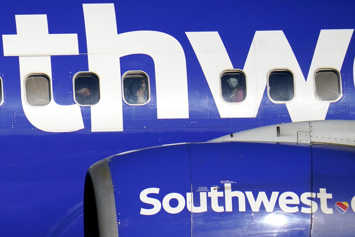 Passengers are seen through the window of a plane with a Southwest logo.
