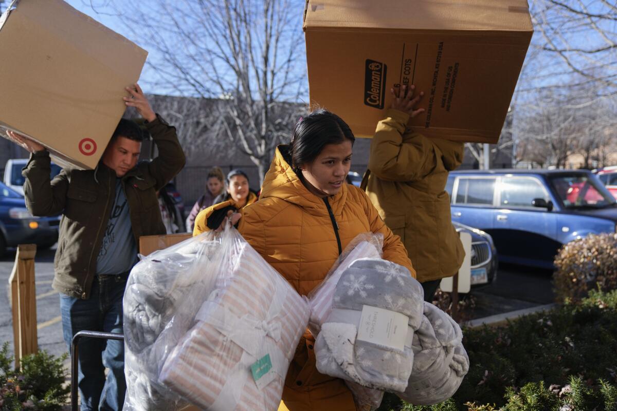 A Venezuelan woman carries supplies in white garbage bags  into the Chicago City Life Center.
