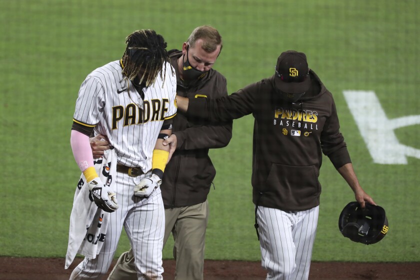 San Diego Padres manager Jayce Tingler, right, and a trainer help Fernando Tatis Jr, left, off the field after Tatis hurt his shoulder while swinging at a pitch in the third inning of a baseball game against the San Francisco Giants, Monday, April 5, 2021, in San Diego. (AP Photo/Derrick Tuskan)