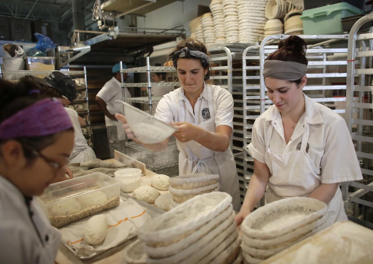 Natasha Portuondo, center, sifts flour over baskets as she and Adina Robles, right, make bread at Zak the Baker, in Miami, on June 5.