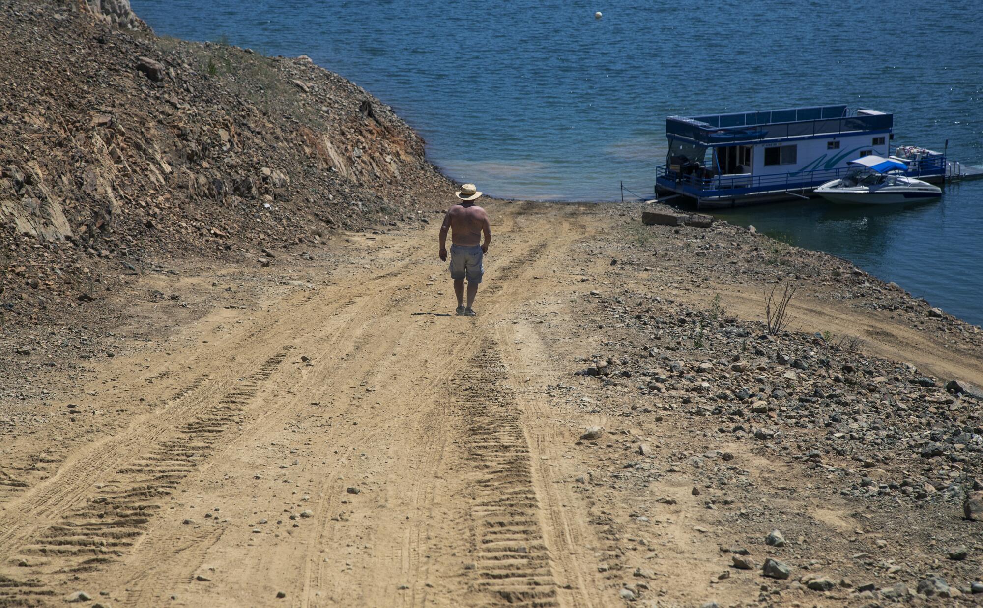 A man walks down a dry ramp, hundreds of feet from the former shoreline marina at Trinity Lake.
