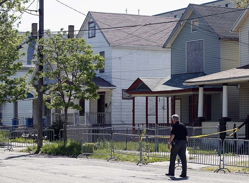 A police officer walks past the house in Cleveland where Ariel Castro allegedly held captive Amanda Berry, Gina DeJesus and Michelle Knight.