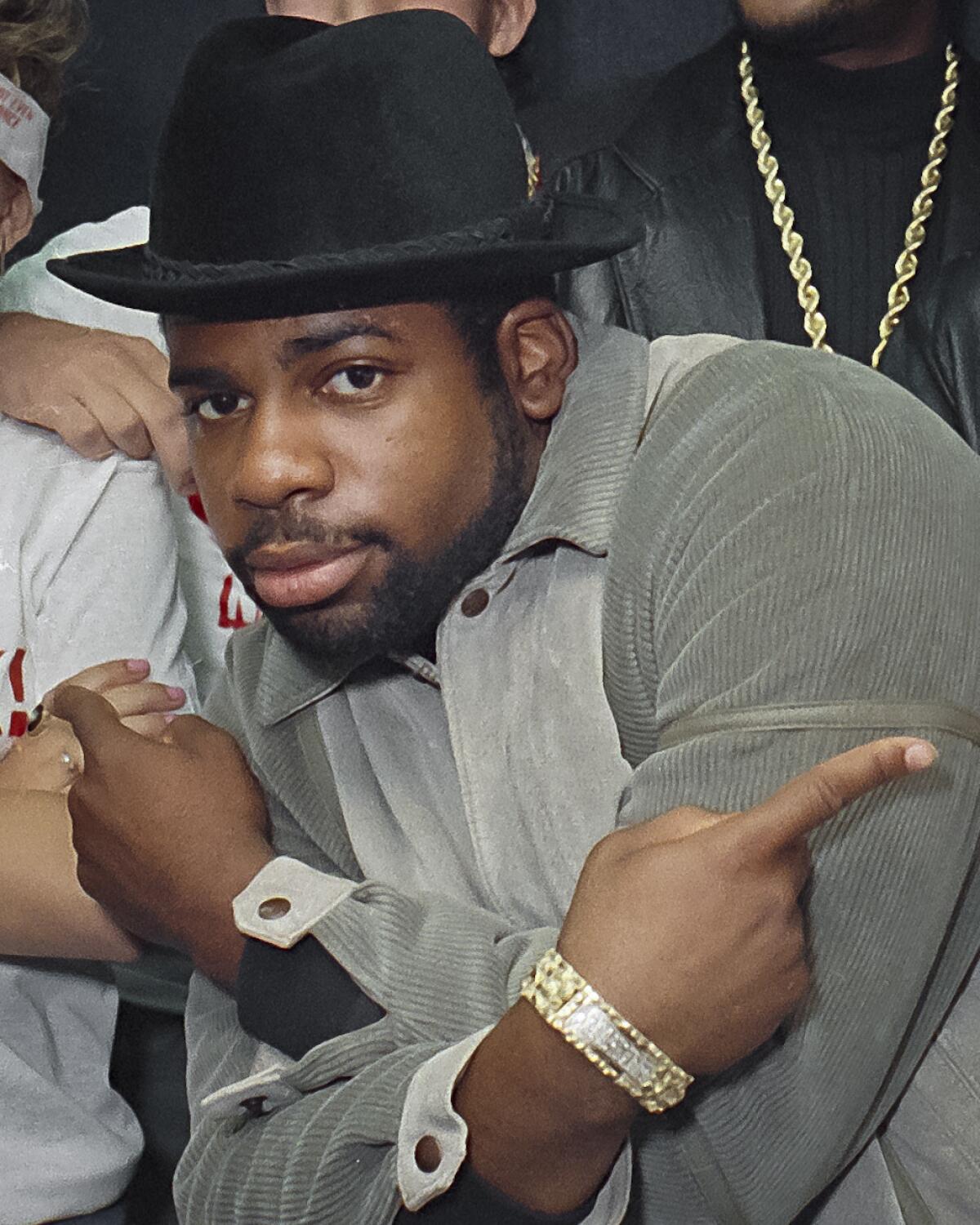 Run-DMC's Jam Master Jay wears a black hat, crosses his arms in an X and points his index fingers