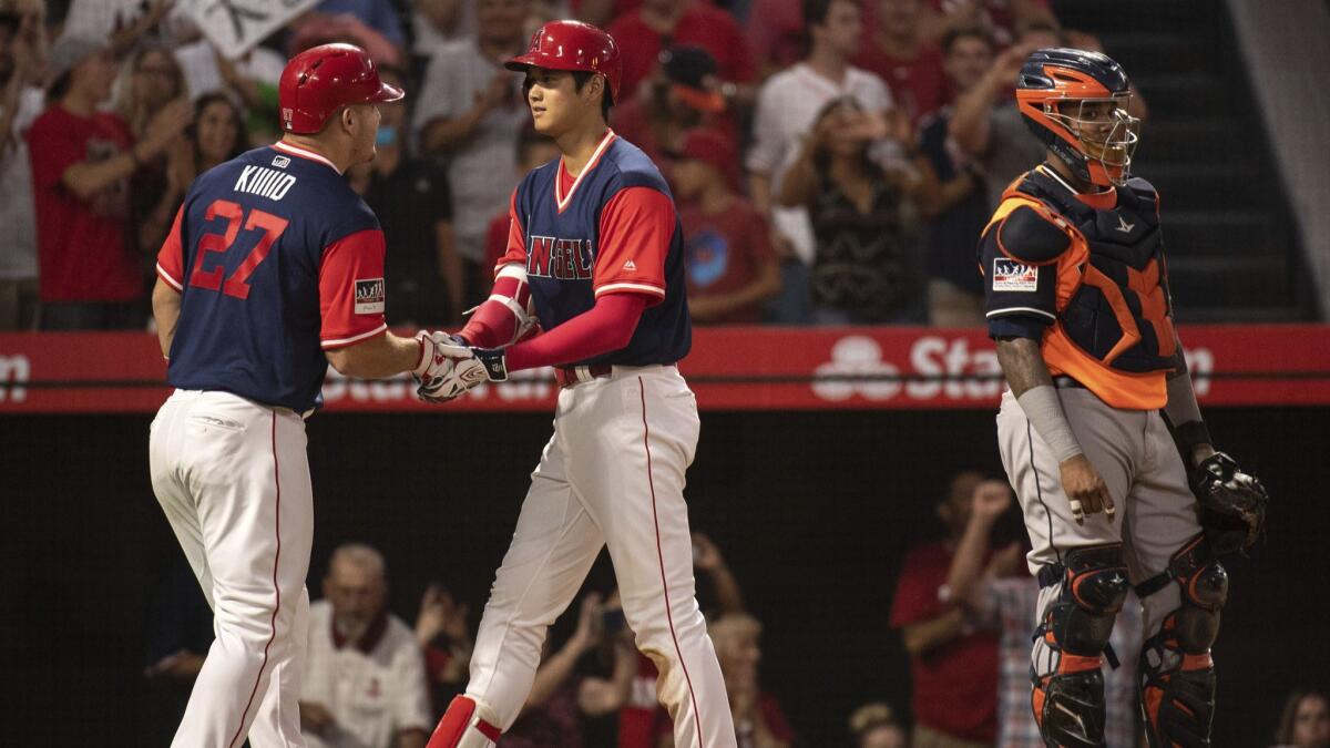Angels' Mike Trout, left, and Shohei Ohtani, center, celebrate Ohtani's two-run home run as Houston Astros catcher Martin Maldonado looks on during the fourth inning.
