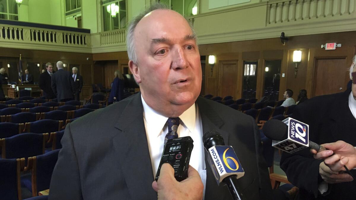 Michigan State University's interim President John Engler speaks with reporters after appearing at a legislative hearing in March in Lansing, Mich.