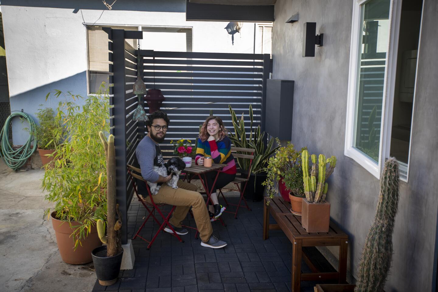 The tenants and their dog sit at a small table on the patio.