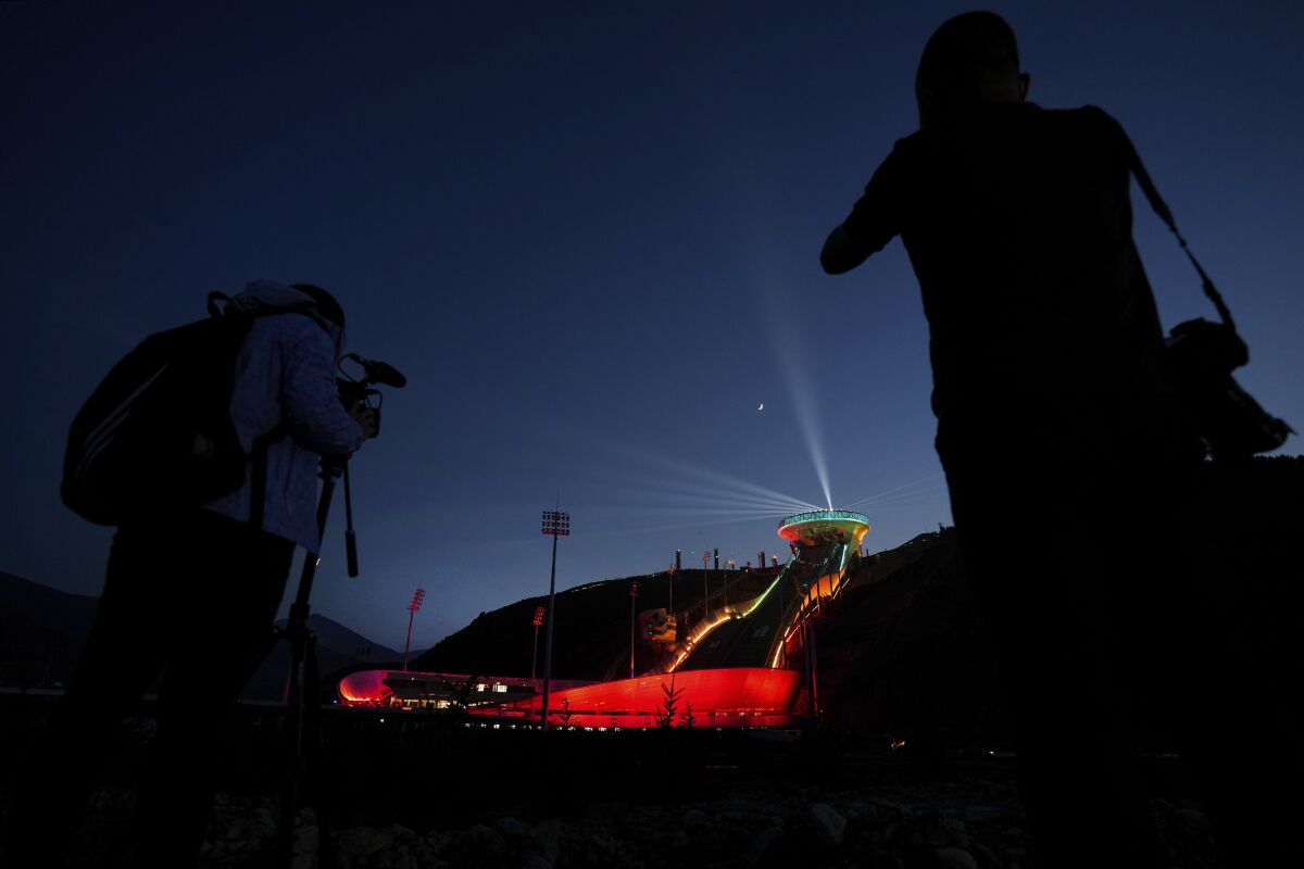 Journalists film a light show at the National Ski Jumping Centre, one of the venues for Beijing 2022 Olympic and Paralympic Winter Games, during a media tour in Zhangjiakou in northwestern China's Hebei province on Wednesday, July 14, 2021. (AP Photo/Andy Wong)